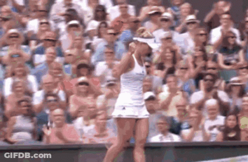 A Woman In A White Dress Is Standing On A Tennis Court In Front Of A Crowd Of People GIF