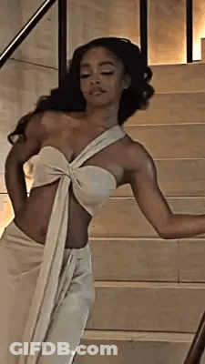 A Woman In A White Dress Is Standing On Stairs . GIF