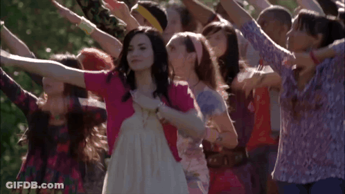 A Woman In A White Dress Is Surrounded By Other Women GIF