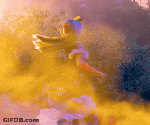 A Woman In A White Dress Is Surrounded By Yellow And Purple Smoke GIF