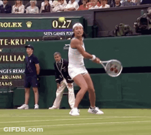 A Woman In A White Dress Is Swinging A Tennis Racquet On A Tennis Court While The Scoreboard Says 0.27 GIF