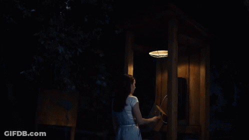 A Woman In A White Dress Is Talking On A Phone GIF