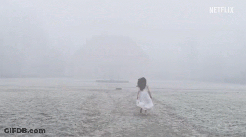 A Woman In A White Dress Is Walking On A Snowy Beach . GIF