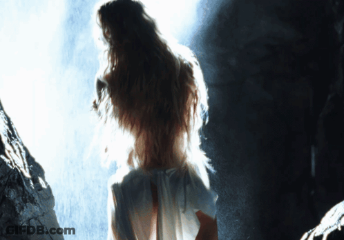 A Woman In A White Dress Stands In A Dark Room GIF