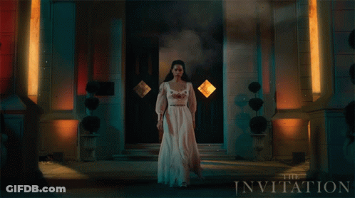 A Woman In A White Dress Stands In Front Of A Building With The Invitation Written On It GIF