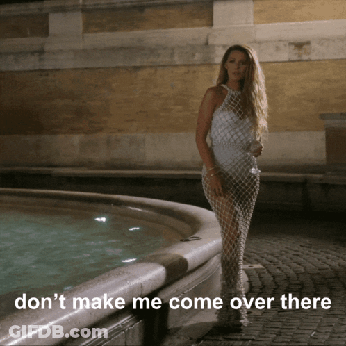 A Woman In A White Dress Stands In Front Of A Fountain With The Words " Don T Make Me Come Over There " GIF