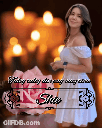 A Woman In A White Dress Stands In Front Of A Pink Rose And A Sign That Says Shute GIF