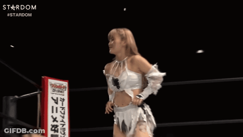 A Woman In A White Dress Stands In Front Of A Sign That Says Divine GIF