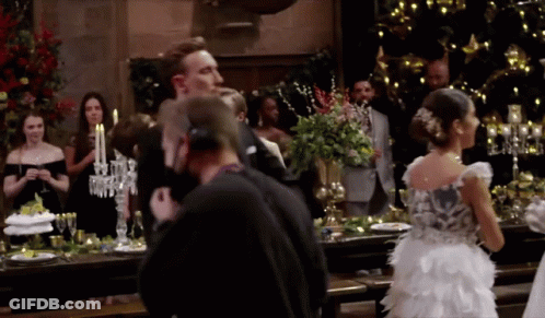 A Woman In A White Dress Stands In Front Of A Table With Candles On It GIF