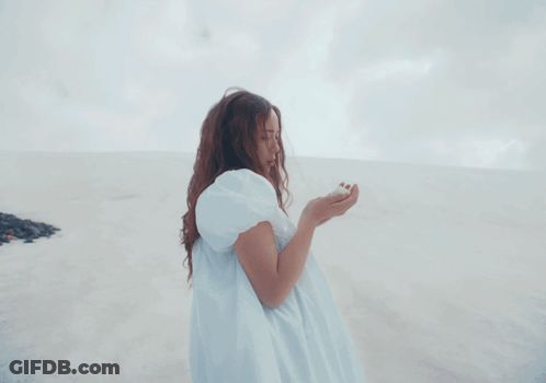 A Woman In A White Dress Stands On A Beach GIF
