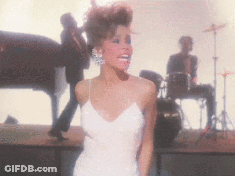 A Woman In A White Dress Stands On A Stage GIF
