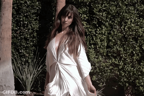 A Woman In A White Dress With A Plunging Neckline GIF