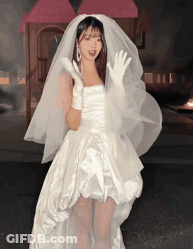 A Woman In A White Dress With A Veil On Her Head GIF