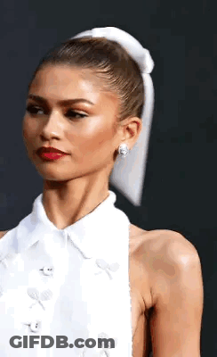 A Woman In A White Dress With A White Bow In Her Hair . GIF