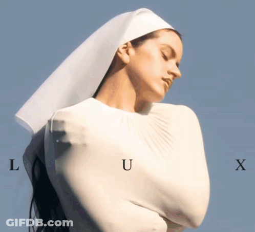 A Woman In A White Dress With The Letters L U And X On Her Chest GIF