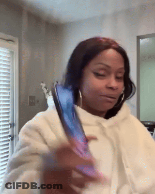 A Woman In A White Hoodie Is Holding A Cell Phone . GIF