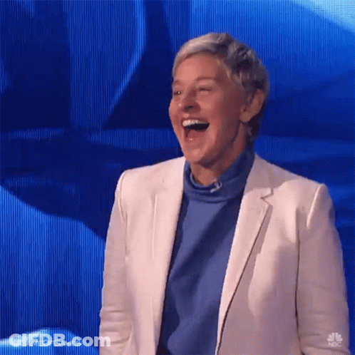 A Woman In A White Jacket And Blue Sweater Is Laughing GIF
