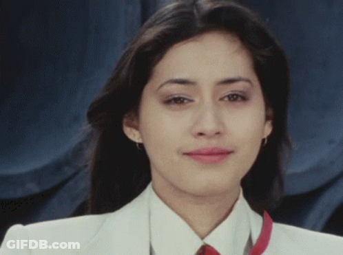A Woman In A White Jacket And Red Tie Is Smiling GIF