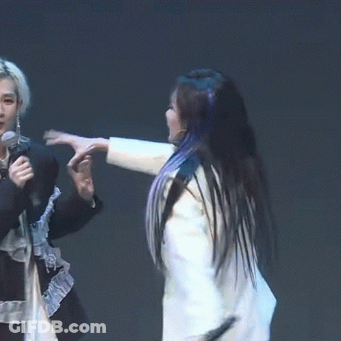 A Woman In A White Jacket Holds A Microphone While A Woman In A Black Shirt Holds A Microphone In Her Hand GIF