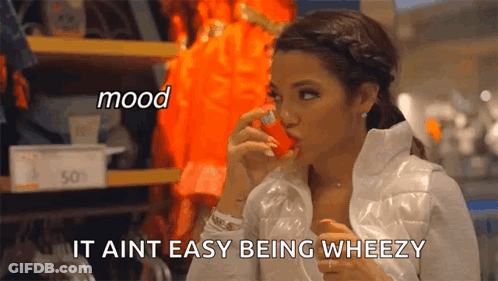 A Woman In A White Jacket Is Holding A Red Object In Her Mouth And Says " It Aint Easy Being Wheezy " GIF