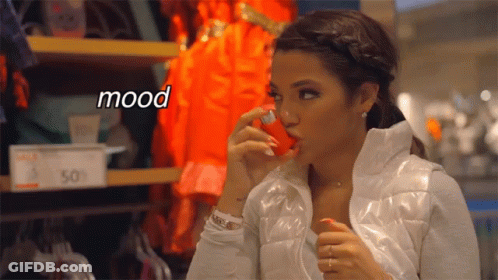 A Woman In A White Jacket Is Holding A Red Object In Her Mouth And The Word Mood Is Above Her GIF