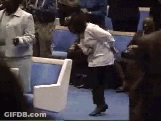 A Woman In A White Jacket Is Kneeling Down In A Crowd Of People GIF
