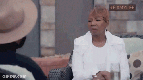A Woman In A White Jacket Is Sitting In A Chair With A Glass Of Water . GIF