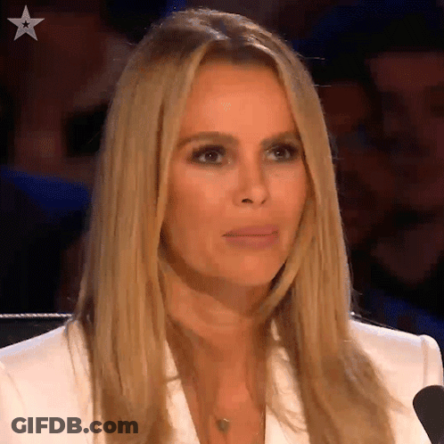A Woman In A White Jacket Is Sitting In Front Of A Microphone And Making A Face . GIF