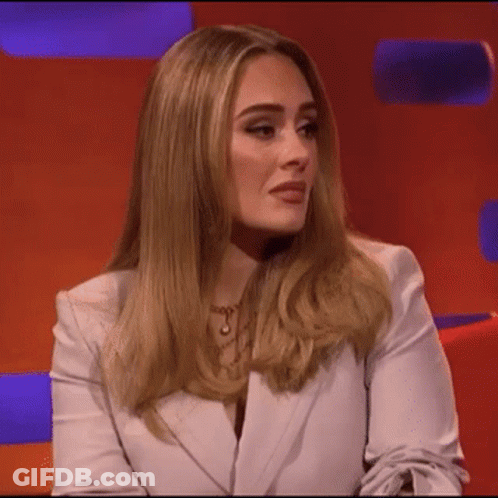 A Woman In A White Jacket Is Sitting On A Red Couch . GIF