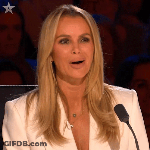 A Woman In A White Jacket Is Speaking Into A Microphone With A Star On Her Chest GIF