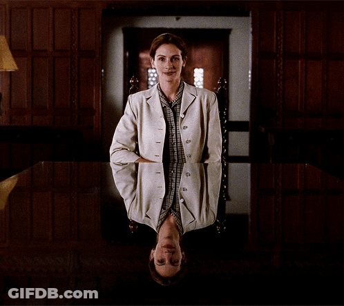 A Woman In A White Jacket Sits In A Chair With Her Head Down GIF