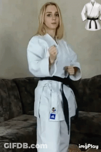 A Woman In A White Karate Uniform Is Standing Next To A Couch . GIF