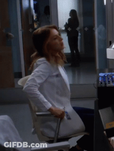 A Woman In A White Lab Coat Is Sitting In A Chair GIF