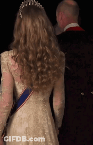 A Woman In A White Lace Dress With A Blue Sash Around Her Waist GIF