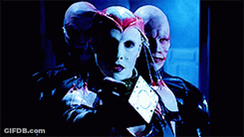 A Woman In A White Mask Is Surrounded By Two Men GIF
