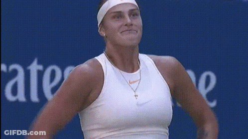A Woman In A White Nike Tank Top Stands In Front Of A Blue Sign That Says Ate GIF