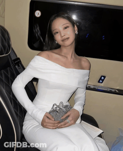 A Woman In A White Off The Shoulder Dress Is Sitting In A Car GIF