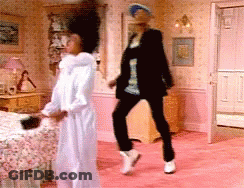 A Woman In A White Robe Is Dancing With A Man In A Black Jacket GIF