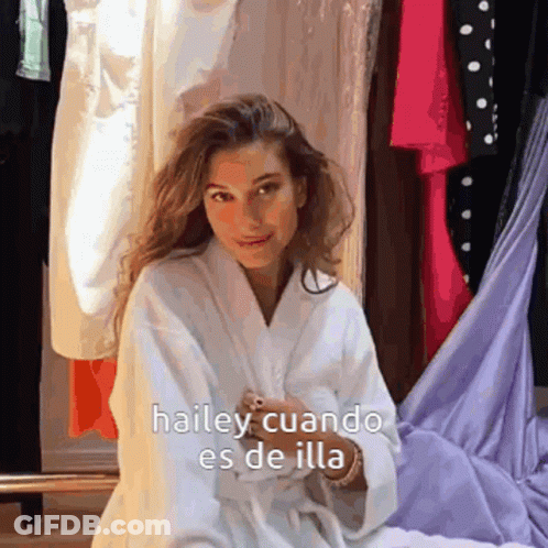 A Woman In A White Robe Is Sitting In Front Of A Closet With The Words Hailey Cuando Es De Illa Written On It GIF