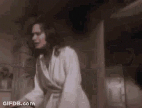 A Woman In A White Robe Is Standing In A Dark Room In A Bathroom . GIF