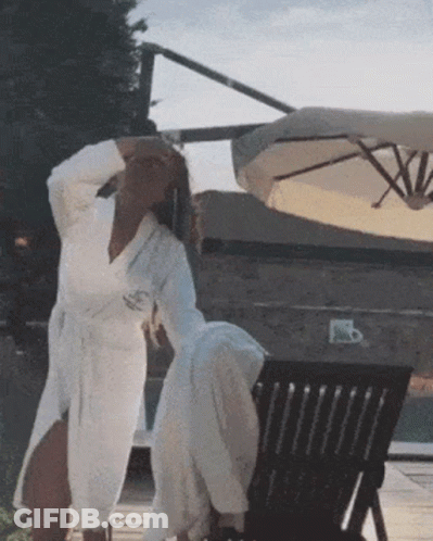 Woman In White Robe Next To Chair GIF