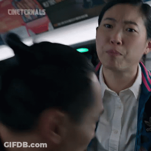 A Woman In A White Shirt And A Blue Jacket Is Looking At Another Woman . GIF