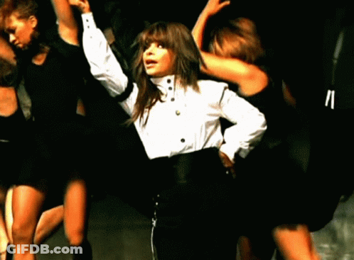 A Woman In A White Shirt And Black Pants Is Surrounded By Other Dancers GIF