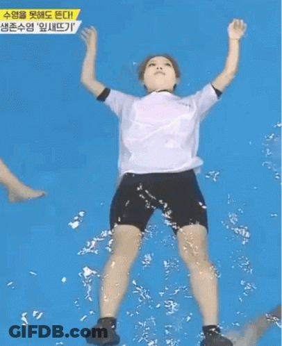 A Woman In A White Shirt And Black Shorts Is Floating In A Swimming Pool . GIF