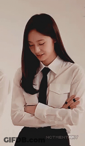 A Woman In A White Shirt And Tie Is Smiling With Her Arms Crossed GIF