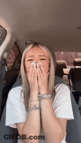 A Woman In A White Shirt Is Covering Her Face With Her Hands GIF