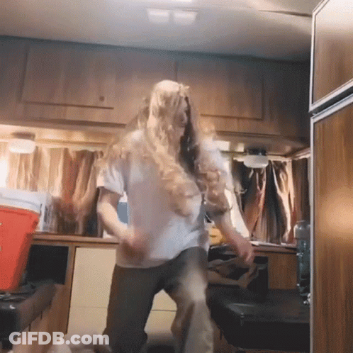 A Woman In A White Shirt Is Dancing In A Kitchen GIF