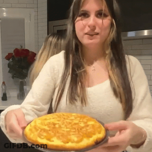 A Woman In A White Shirt Is Holding A Pie GIF