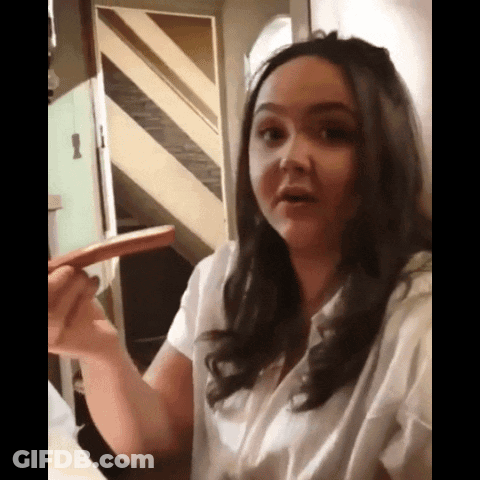 A Woman In A White Shirt Is Holding A Sausage In Her Hand GIF