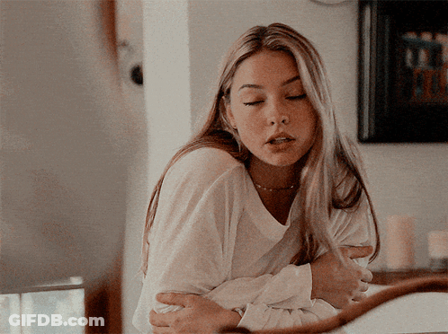 A Woman In A White Shirt Is Hugging Another Woman GIF